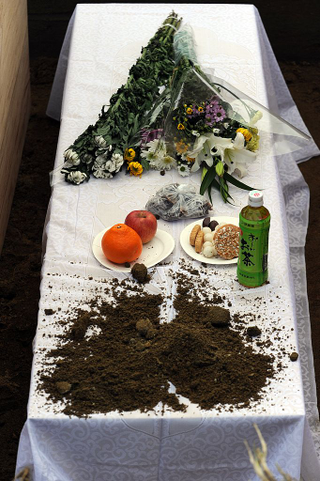 Food and drinks left on the coffin of someone who died during the 2011 tsunami in Japan (Photo: Toshifumi Kitamura/Getty Images)